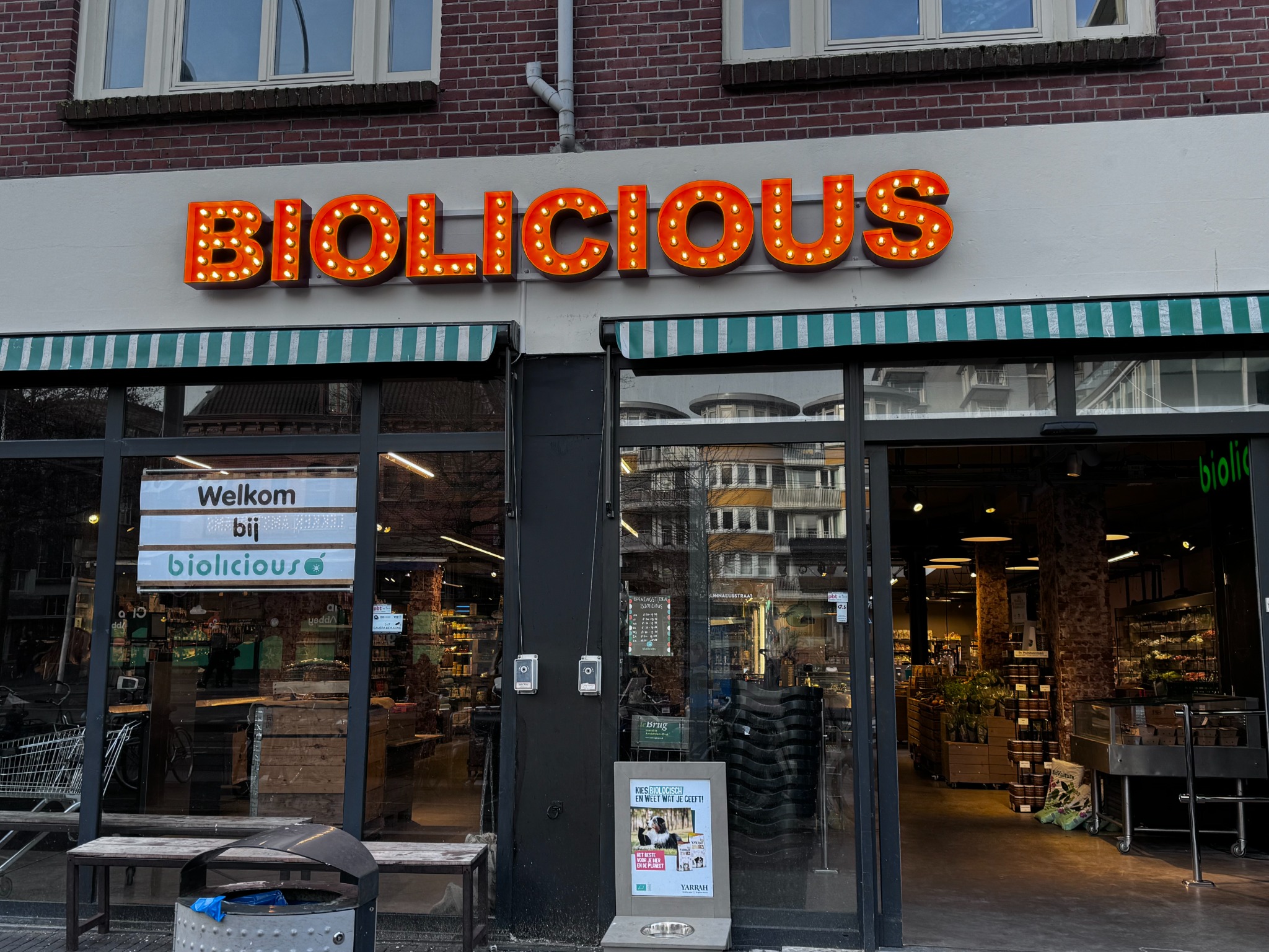 De ingang van Biolicious met het oranje verlichte winkelbord
